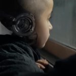 The Creator: Ein Junge, offenbar ein Android, blickt verträumt aus dem Fenster.
