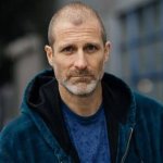 Der Schauspieler Stewart McLean blickt in die Kamera. Er trägt einen Kapuzenpullover.