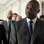 Heads of State: Idris Elba spielt den englischen Premierminister und steht in einem Gang, und hinter ihm stehen Leute aus seinem persönlichen Stab.