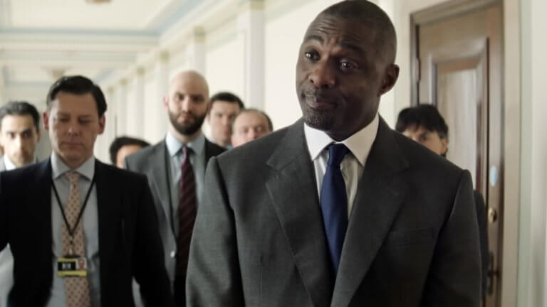 Heads of State: Idris Elba spielt den englischen Premierminister und steht in einem Gang, und hinter ihm stehen Leute aus seinem persönlichen Stab.
