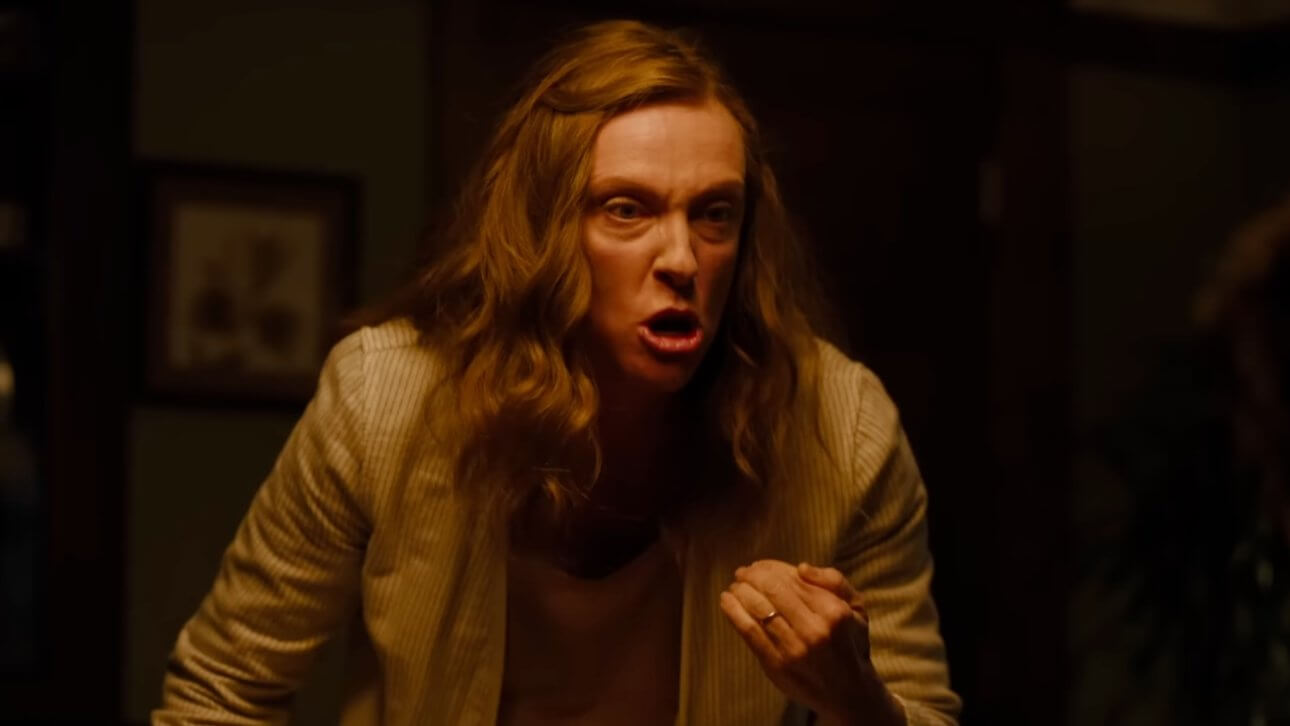 Hereditary: Toni Collette steht in einer Wohnung und wirkt sehr wütend. Ihr Haar ist durcheinander. Das Licht unterstreicht die gespannte Atmosphäre.