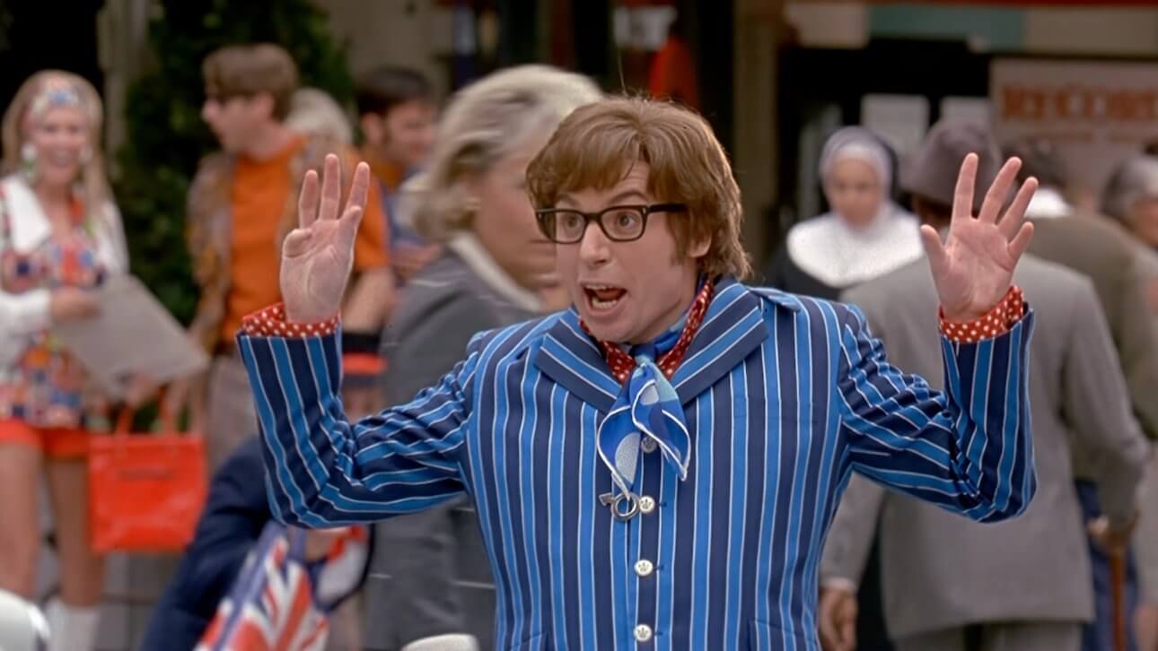 Austin Powers: der Comedian Mike Myers als Austin Powers trägt einen gestreiften Anzug und führt auf offener Straße einen Tanz auf, während ihn Passanten beobachten.