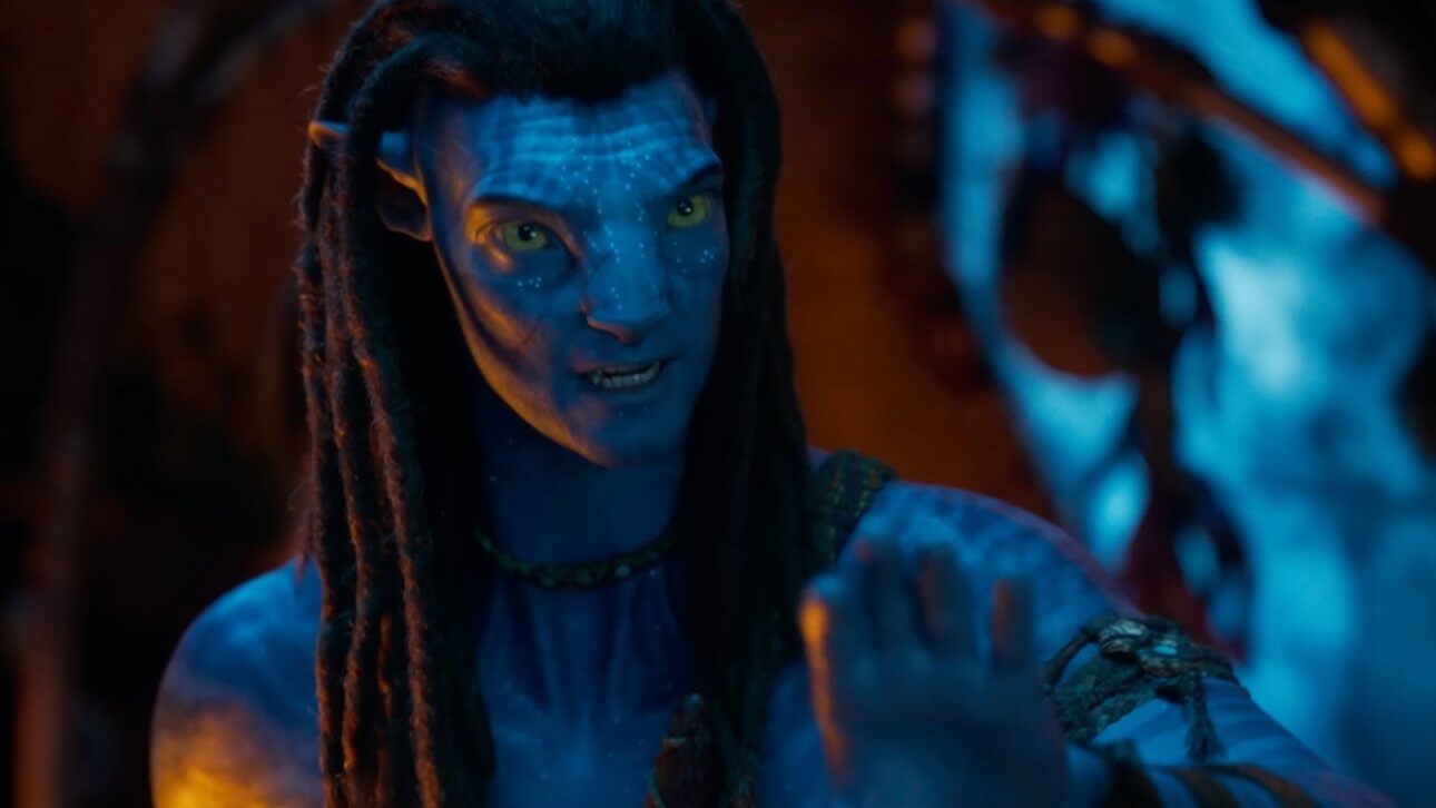 Avatar: Fire and Ash: Ein außerirdisches Wesen mit blauer Hand und humanoiden Zügen in einer durch ein Lagerfeuer erhellten Höhle.