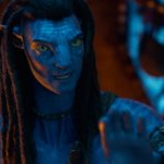 Avatar: Fire and Ash: Ein außerirdisches Wesen mit blauer Hand und humanoiden Zügen in einer durch ein Lagerfeuer erhellten Höhle.