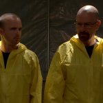 Breaking Bad: Walter White und sein Compagnon tragen gelbe Schutzanzüge und stehen in einem schlecht beleuchteten Lagerraum.