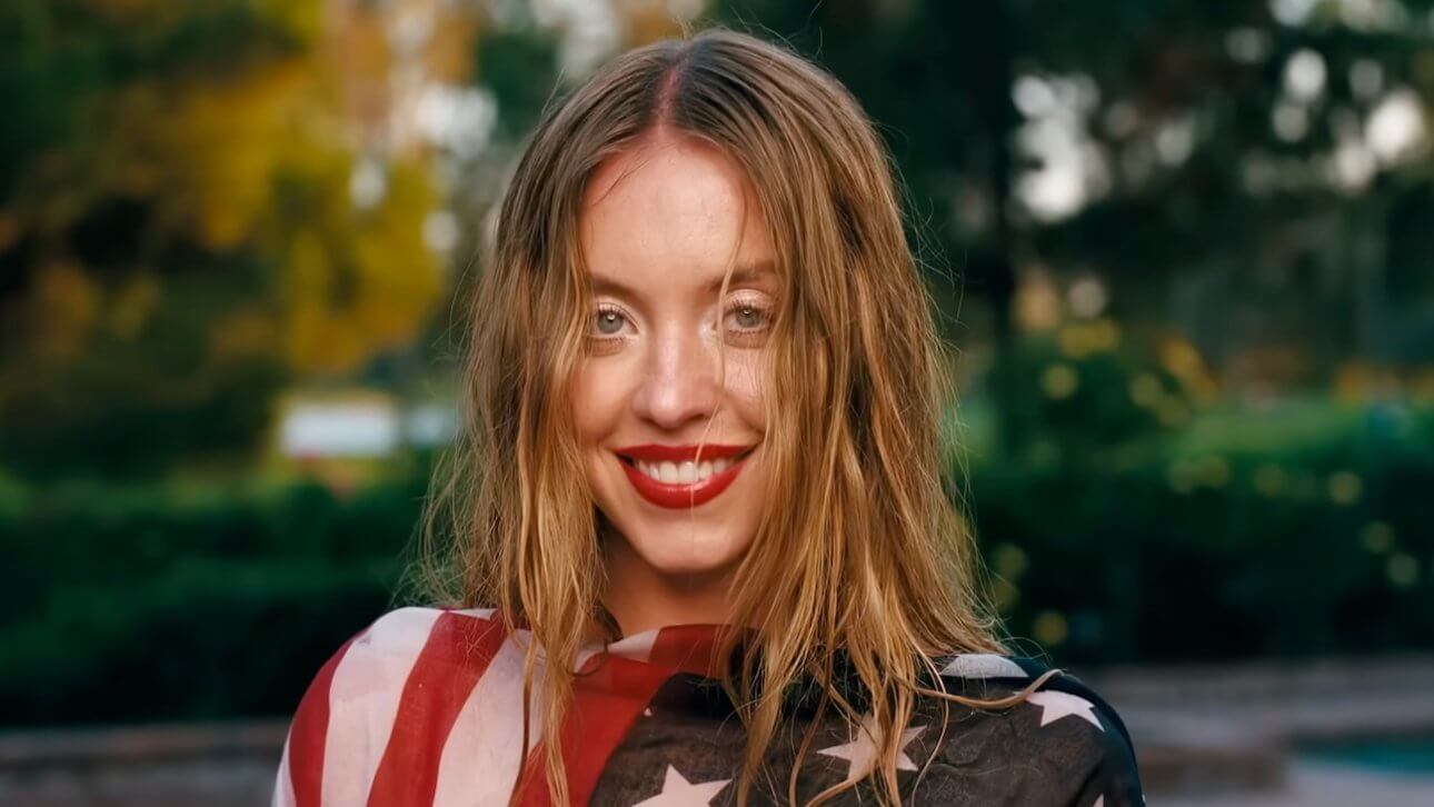 EUPHORIA Staffel 3: Sydney Sweeney steht in einem Garten, trägt die US-Flagge als Oberteil und ihre Haare sind etwas durcheinander.