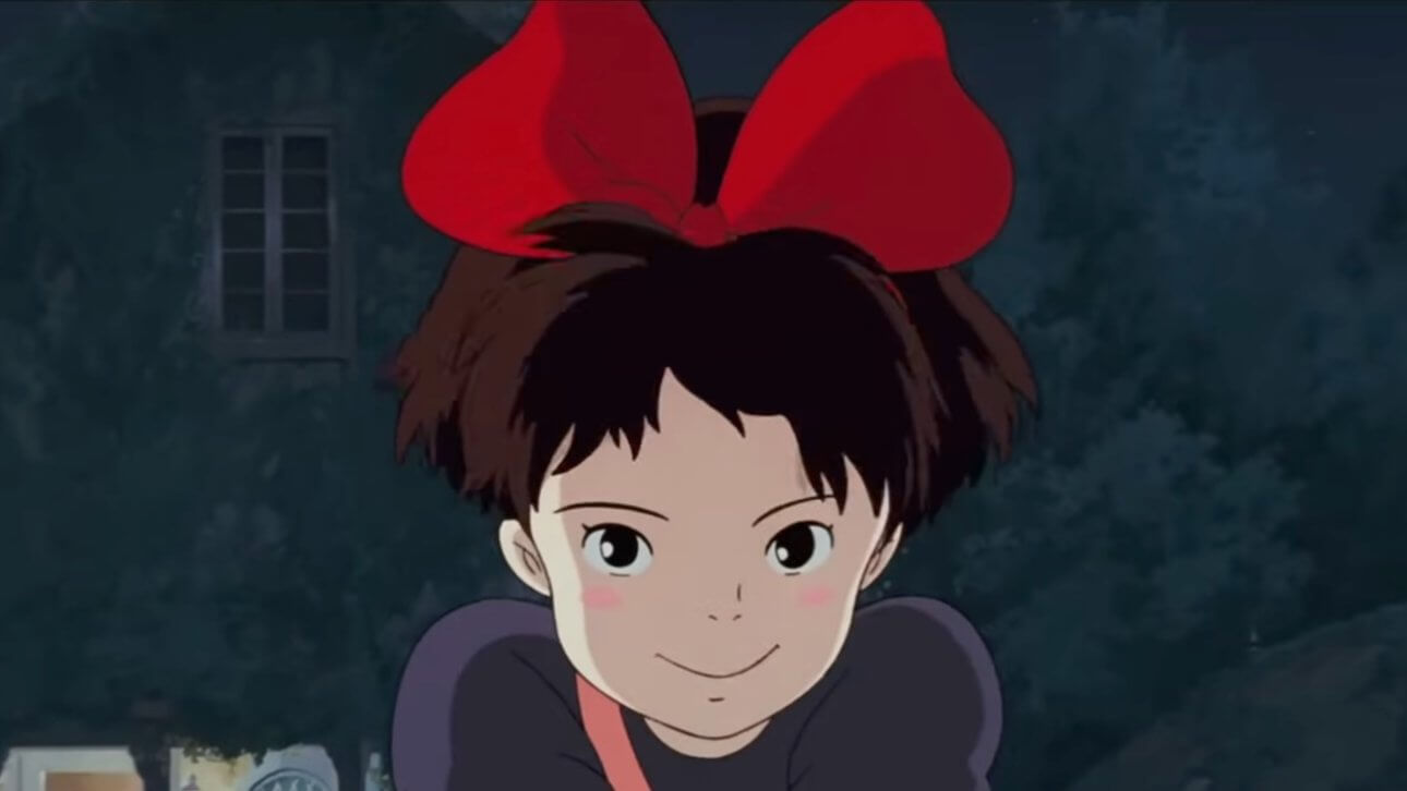 Kiki's Delivery Service: die Zeichentrickfigur Kiki lächelt in die Kamera und hat eine rote Schleife im Haar.