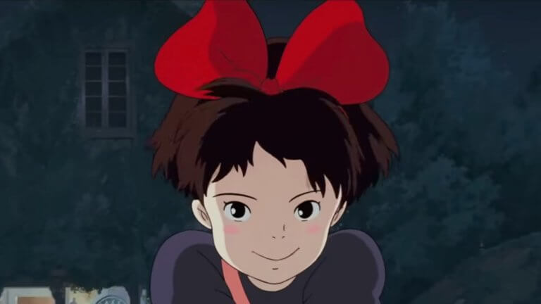 Kiki's Delivery Service: die Zeichentrickfigur Kiki lächelt in die Kamera und hat eine rote Schleife im Haar.