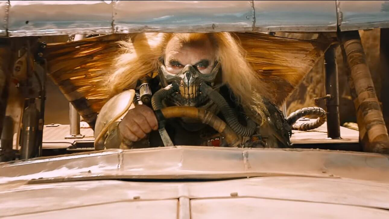 Mad Max: Fury Road: ein Bösewicht in typischer Endzeit-Montur sitzt am Steuer seines Fahrzeugs und blickt entschlossen auf die Straße.