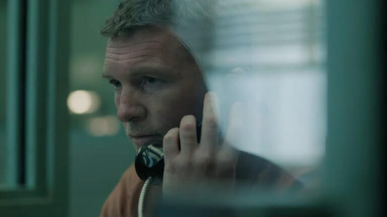 Nur für dein Leben: Sam Worthington sitzt in seiner Gefängnismontur im Besucherraum hinter Glas und spricht per Telefon mit einer Journalistin, die auf der anderen Seite der Glasscheibe sitzt.