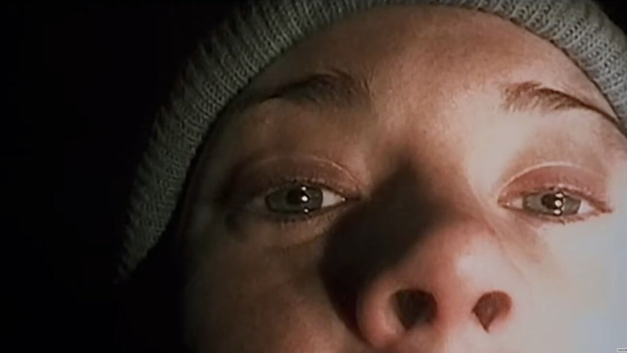 The Blair Witch Project: es ist die obere Gesichtshälfte einer verängstigten jungen Frau zu sehen, und sie trägt eine beige Wollmütze.