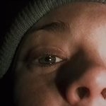 The Blair Witch Project: es ist die obere Gesichtshälfte einer verängstigten jungen Frau zu sehen, und sie trägt eine beige Wollmütze.
