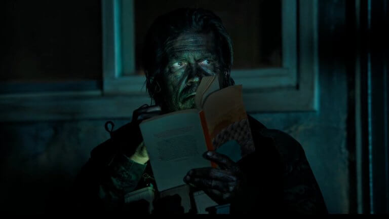 The Dog Stars: Josh Brolin sitzt in einem dunklen Raum und hält ein Buch in der Hand.