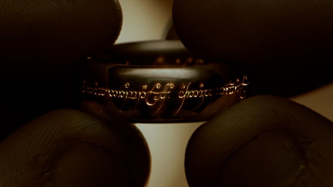 The Fellowship of the Ring | The Lord of the Rings: der eine Ring wird von zwei Daumen und zwei Zeigefingern gehalten.