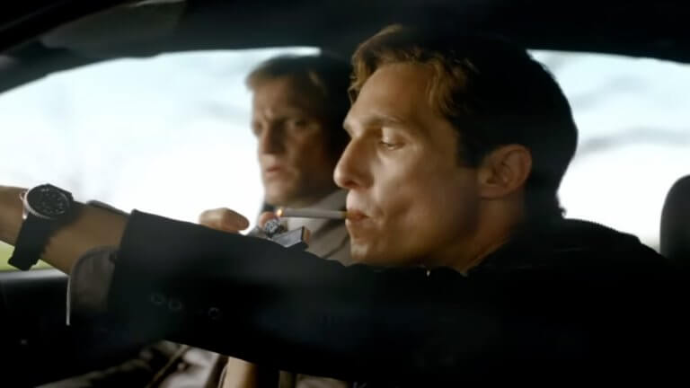 True Detective - Season 1: Woody Harrelson und Matthew McConaughey sitzen zusammen im Auto, und Matthew McConaughey zündet sich eine Zigarette an.