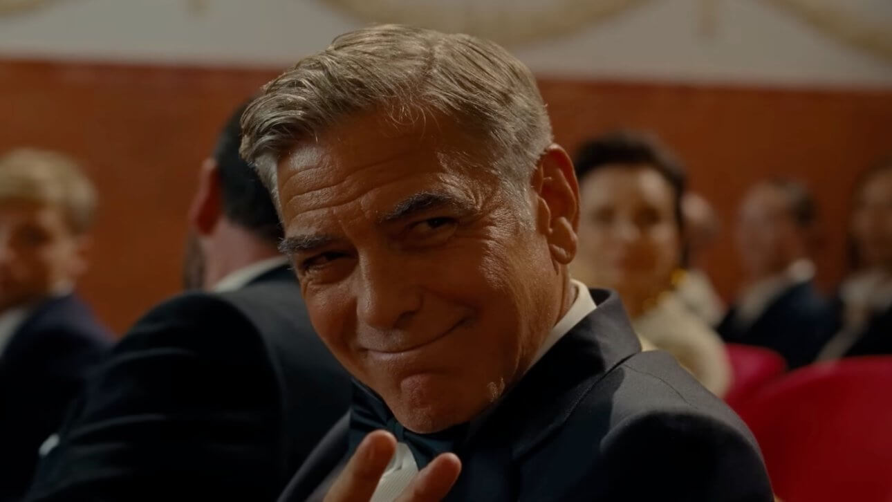 Jay Kelly: George Clooney trägt einen Smoking und grüßt freundlich eine Person, die nicht im Bild ist.