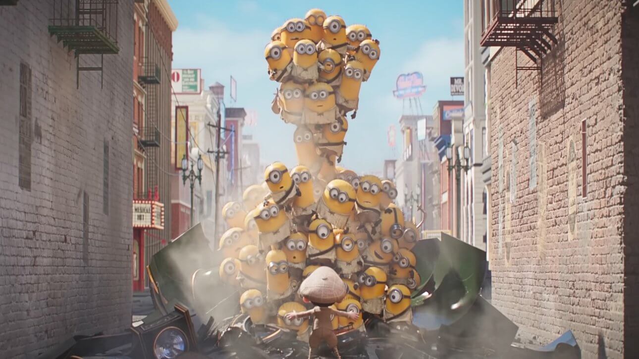 Minions & Monsters: viele kleine Minions bauen sich zu einer Wand auf. Vor ihnen steht eine kleine Person mit Mütze, die offensichtlich versucht, die Minions aufzuhalten.