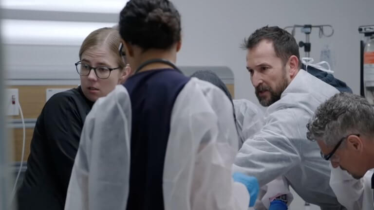 The Pitt: die Ärzte sind über einen Patienten gebeugt und versuchen, ihm das Leben zu retten.