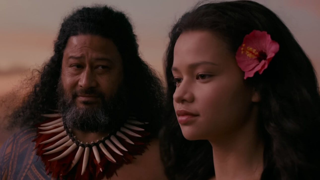 Moana: Moana und ein hawaiianischer Eingeborener stehen am Strand und unterhalten sich.