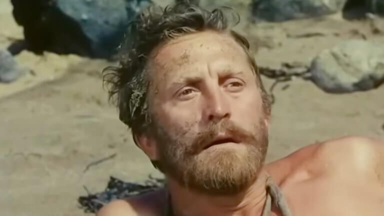 Die Fahrten des Odysseus: Kirk Douglas sitzt erschöpft am Strand und blickt in die Ferne.