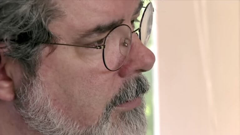 The Beginning: Making Star Wars: Episode I The Phantom Menace: eine nahe Aufnahme von George Lucas, der eine Brille trägt und einen Vollbart