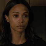 Lioness: Die Schauspielerin Zoe Saldana steht vor einem dunkelbraunen Schrank. Im Vordergrund ist der schemenhafte Umriss einer blonden Frau erkennbar.