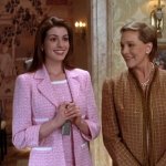 Plötzlich Prinzessin 2: Anne Hathaway trägt ein rosanes Outfit. Neben ihr ist eine etwas ältere Frau mit Perlenkette. Sie stehen in einem Raum, der sehr klassisch und luxuriös eingerichtet wurde.