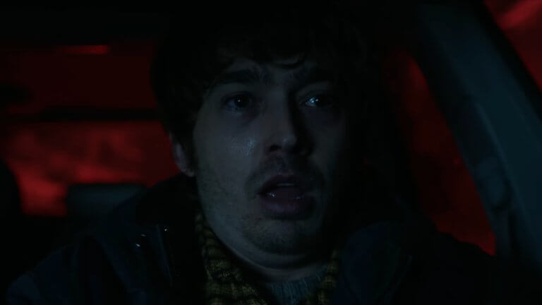 RESIDENT EVIL: ein sichtlich gestresster junger Mann sitzt in seinem Auto.