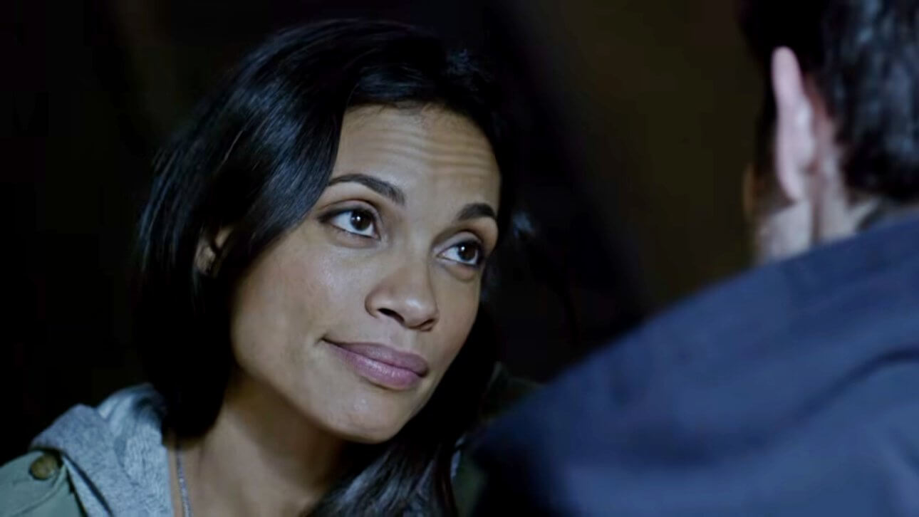 Rosario Dawson blickt als Claire Temple in der Serie Daredevil Matt Murdock an. Auf ihrer Stirn sind leichte Sorgenfalten zu erkennen, während sie leicht lächelt.