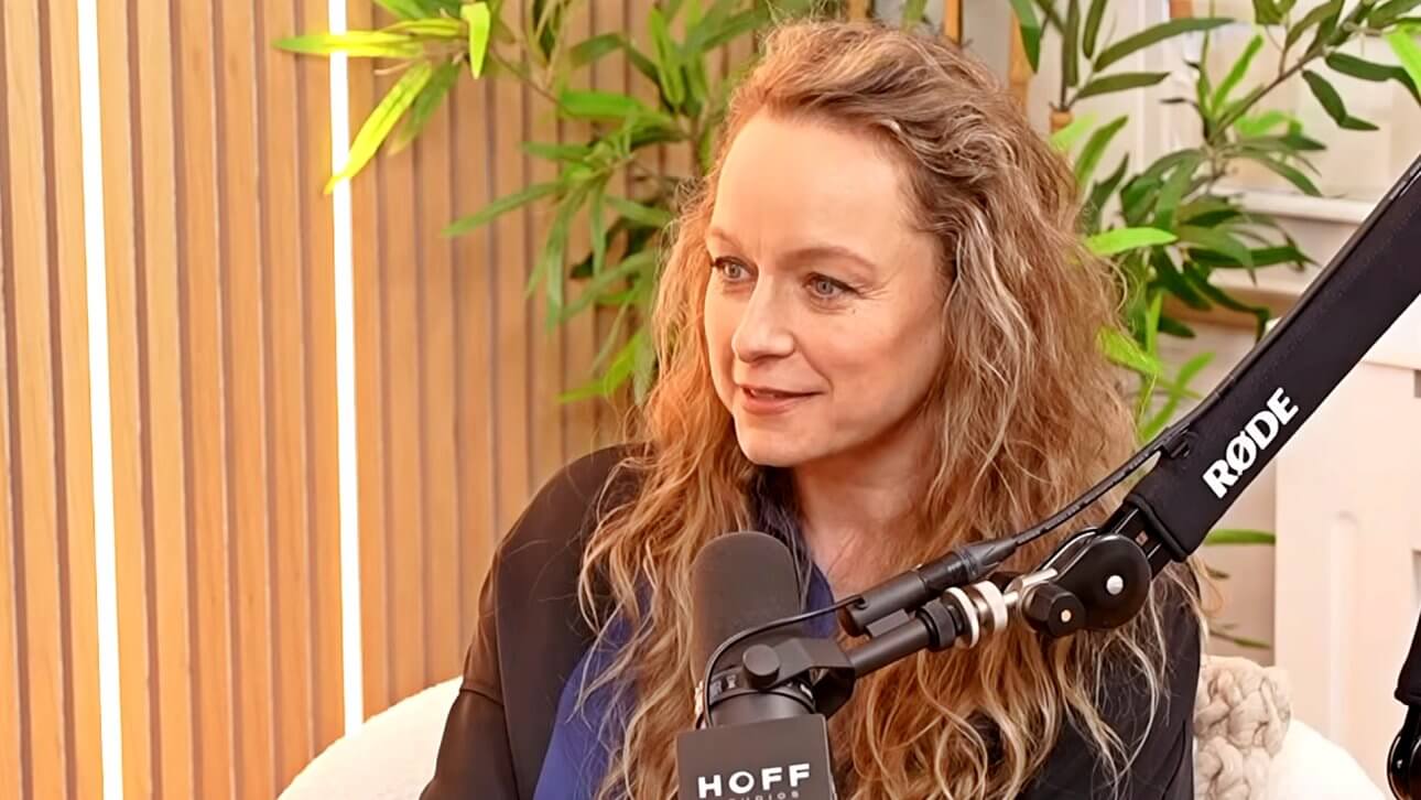 Samantha Morton sitzt im Studio des Podcasts Happy Sad Confused. Hinter ihr steht eine Pflanze und vor ihr ist ein Mikrofon zu sehen.
