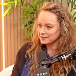 Samantha Morton sitzt im Studio des Podcasts Happy Sad Confused. Hinter ihr steht eine Pflanze und vor ihr ist ein Mikrofon zu sehen.