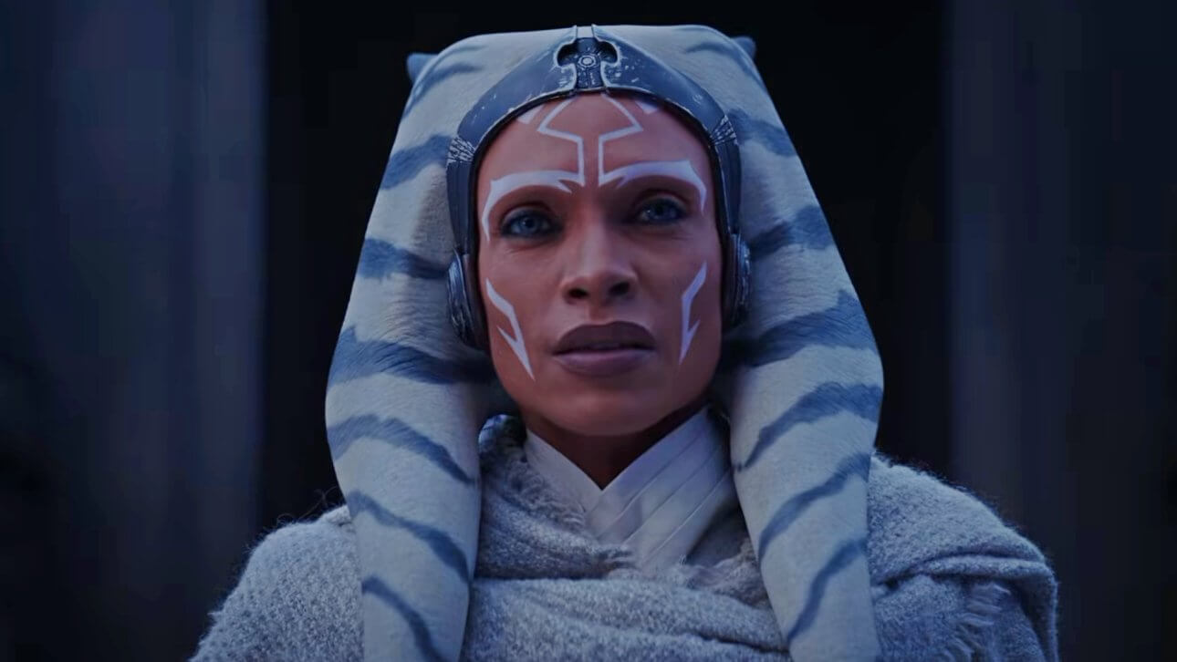 Rosario Dawson blickt als Ahsoka Tano in Richtung Kamera. Sie trägt einen grauen Umhang über einer weißen Robe.