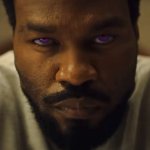 Yahya Abdul-Mateen II blickt in der Rolle von Simon Williams ernst in die Kamera. Seine Augen leuchten in einem intensiven Violett.