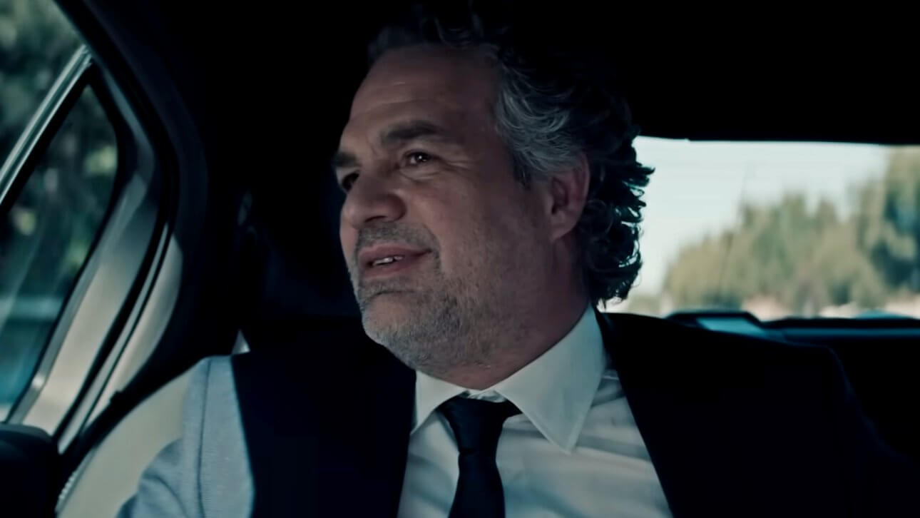 Mark Ruffalo blickt aus dem Seitenfenster eines Autos. Er trägt einen Anzug und ein leichtes Lächeln umspielt seine Lippen.