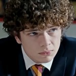 Noah Jupe blickt mit einem unergründlichen Gesichtsausdruck zur Seite. Er trägt eine Schuluniform und hinter ihm sitzen Klassenkameraden.