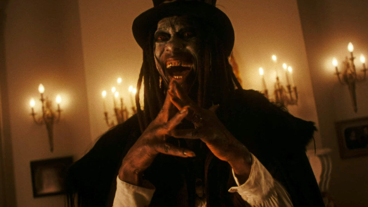 Der Vodoo-Meister Papa Legba lacht manisch und legt die Fingerspitzen aneinander. Seine Augen leuchten blutrot, während der Raum, in dem er steht, von alten Lampen an der Wand erhellt wird.