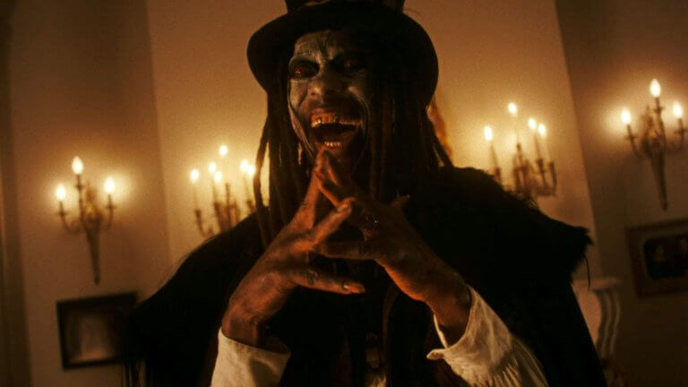 Der Vodoo-Meister Papa Legba lacht manisch und legt die Fingerspitzen aneinander. Seine Augen leuchten blutrot, während der Raum, in dem er steht, von alten Lampen an der Wand erhellt wird.